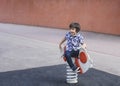 Active kid sitting on rocking chairs in the playground, Happy Child boy having fun playing outdoor in the park on Summer Royalty Free Stock Photo