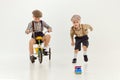 Active kids. Boys, childred in retro clothes riding vintage bicycle over grey studio background. Concept of game Royalty Free Stock Photo