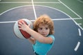 Active kids lifestyle. Little caucasian sports kid playing basketball holding ball with happy face.