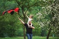 Active leisure. Running with red kite. Child sitting on the man`s shoulders. Having fun