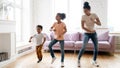 Black children and young babysitter dancing in living room