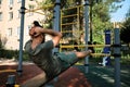 Active lifestyle concept. Young cute Caucasian man shakes his abs on street sports ground equipped with exercise equipment. Royalty Free Stock Photo