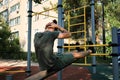 Active lifestyle concept. Young cute Caucasian man shakes his abs on street sports ground equipped with exercise equipment. Royalty Free Stock Photo