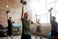 Active Lifestyle. Young athletic man lifting dumbbell while having workout at industrial gym. Group training concept Royalty Free Stock Photo