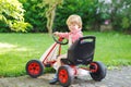 Active little boy driving pedal car in summer garden Royalty Free Stock Photo