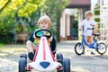 Active little boy driving pedal car in summer garden Royalty Free Stock Photo