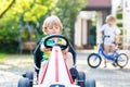 Active little boy driving pedal car in summer garden Royalty Free Stock Photo