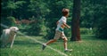 Active little boy running playing with dog on field with sprinklers on sunny day Royalty Free Stock Photo