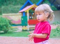 Active little Caucasian girl in a red t-shirt and with tails on playground - closeup shot