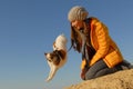 Active little chihuahua dog jumping from beautiful girl owner shoulder during agility training on yellow sand with blue sky Royalty Free Stock Photo