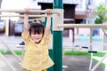 Active little child girl playing on playground. Children hands holding with workout machine hung on the gymnastic bar.