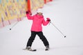 Active little girl in pink ski suit skiing on winter snow hill holding poles during christmas eve holiday vacation leisure Royalty Free Stock Photo