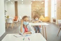 Active little girl wearing protective face mask during coronavirus outbreak raised her hand in class. School kid Royalty Free Stock Photo