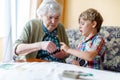 Active little preschool kid boy and grand grandmother playing card game together at home