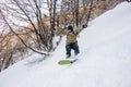 Active male snowboarder dressed in a grey brown sportswear riding down the sountain slope Royalty Free Stock Photo
