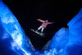 Active male snowboarder dressed in a white and pink sportswear jumping between the snow slopes Royalty Free Stock Photo