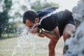 Active male sportsperson takes a refreshing break in park, washing face and hydrating. Royalty Free Stock Photo