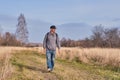 Active man in casual with backpack is walking in a meadow late autumn. Siberia, Russia Royalty Free Stock Photo