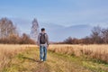 Active man in casual with backpack is walking in a meadow late autumn. Siberia, Russia Royalty Free Stock Photo