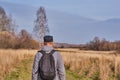 Active man in casual with backpack is walking in a meadow late autumn. Siberia, Russia Royalty Free Stock Photo