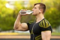 Active man drinking water from a bottle, outdoor. Muscular male quenches thirst Royalty Free Stock Photo