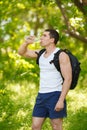 Active man drinking water from a bottle, outdoor. Young muscular male quenches thirst Royalty Free Stock Photo