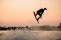 active man jumping over splashing wave on wakeboard holding on to the rope. Water sports activity. Royalty Free Stock Photo