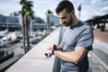 Active man looking swatch during exercise outside. Fitness male looking his smartwatch checking running time after