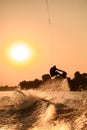 active man making trick with wakeboard on bright orange sky and sun background. Royalty Free Stock Photo