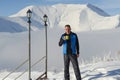 Active man relaxing at the ski resort, standing with cup of coffee on the background of snow-capped mountains in the clouds and e Royalty Free Stock Photo