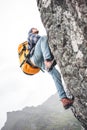 Active man tourist wearing professional backpack to climb on the rock