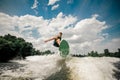 Active man wakesurfing on the board down the river against the cloudy sky and trees Royalty Free Stock Photo