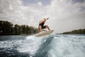 Active man wakesurfing and jumping on the white board down the b Royalty Free Stock Photo