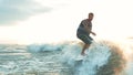 Active man wakesurfing in slow motion. Wakeboarder surfing across river.