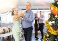 Active mature men and women dancing samba dances in ballroom during celebration Christmas and New Year