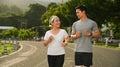 Active middle aged woman jogging with personal trainer at the park in evening. Healthy lifestyle and fitness concept Royalty Free Stock Photo