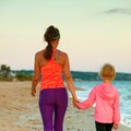 Active mother and child on seacoast in evening walking