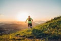 Active mountain trail runner dressed bright t-shirt with backpack running endurance marathon race by picturesque hills at sunset