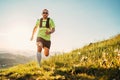 Active mountain trail runner dressed bright t-shirt with a backpack in sports sunglasses running endurance marathon race by