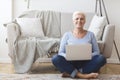 Active old woman sitting on floor and using laptop Royalty Free Stock Photo