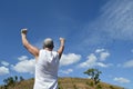 Active older man with arms up in sign of success or achievement on the hill.