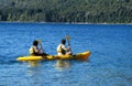 Active people in kayaks wearing lifejackets with paddles