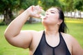 Active plus size woman hydration drinking a water bottle outdoors, taking a break during a sunny day exercise routine. Royalty Free Stock Photo