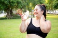 Active plus size woman hydration drinking a water bottle outdoors, taking a break during a sunny day exercise routine. Royalty Free Stock Photo