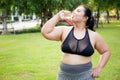 Active plus size woman hydration drinking a water bottle outdoors, taking a break during a sunny day exercise routine. Royalty Free Stock Photo