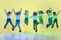 Active, positive little girls, children in sportive, casual clothes dancing, jumping against green studio background in Royalty Free Stock Photo