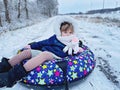 Active prechool girl sliding down the hill on snow tube. Cute little happy child having fun outdoors in winter on sledge