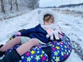 Active prechool girl sliding down the hill on snow tube. Cute little happy child having fun outdoors in winter on sledge