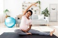 Active pregnancy. Smiling black future mom stretching her legs, doing her morning yoga workout on mat at home gym Royalty Free Stock Photo