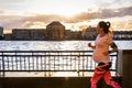 Pregnant woman running outside in a city at the riverside